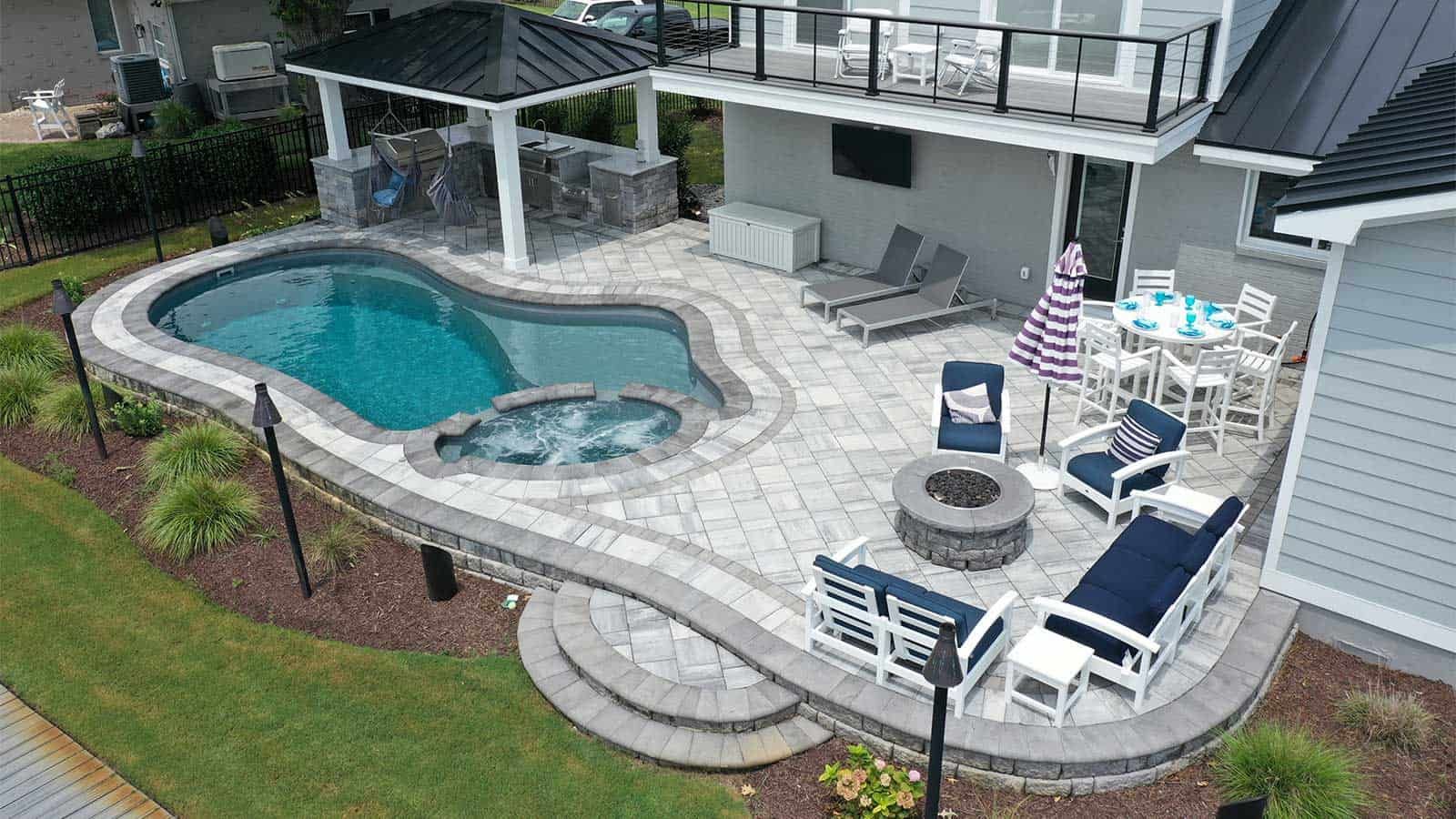 Outdoor hardscape with pavers by a fiberglass pool