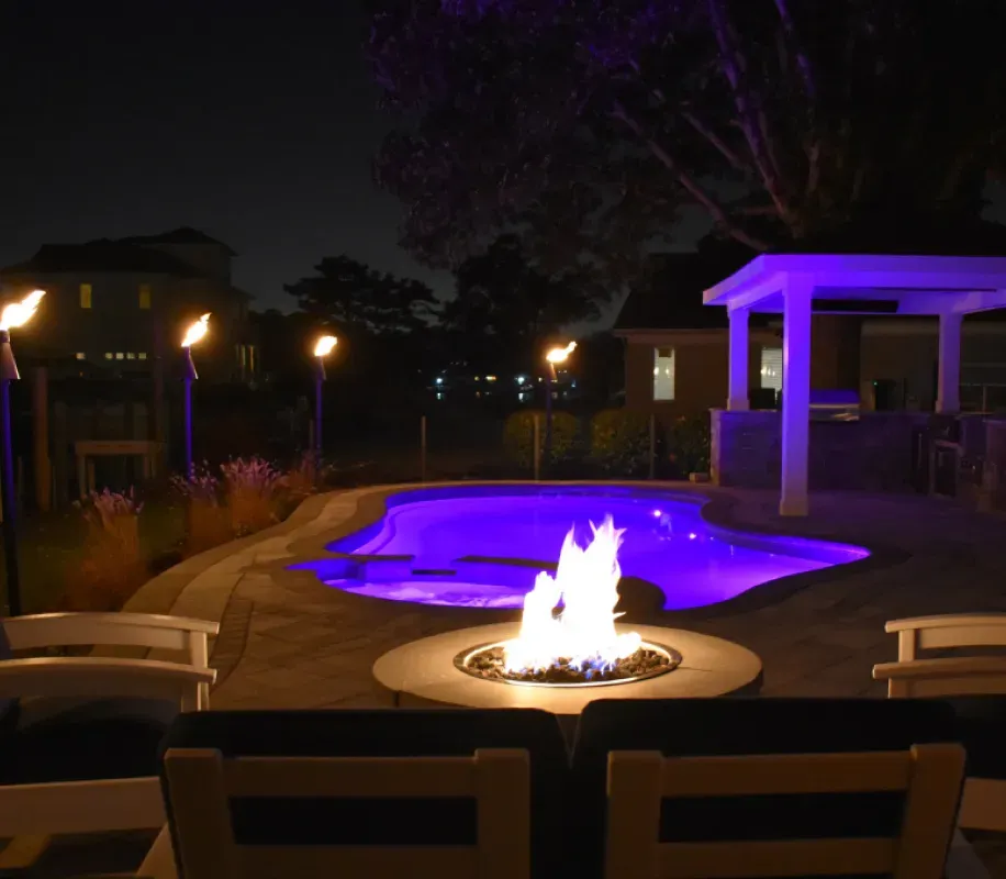 Firepit next to fiberglass pool with custom fire features. 