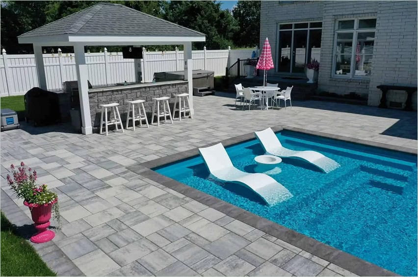 Hardscape and outdoor kitchen surrounding a fiberglass pool installed by Solid Structures.