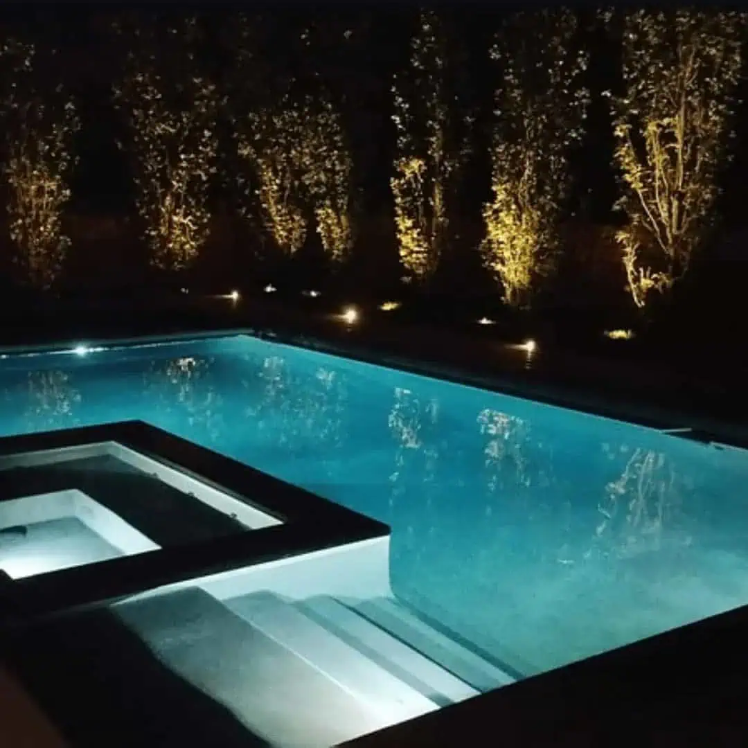 Fiberglass swimming pool in Virginia Beach, illuminated at night with integrated outdoor lighting.